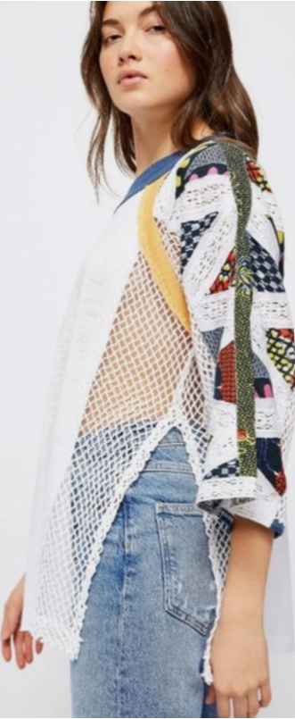 Woman wearing a colorful, patterned cardigan over a white shirt with blue jeans on a white background